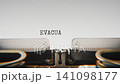 Old mechanical typewriter typing Evacuation in a close up view, with metal letters striking the white paper. 141098177