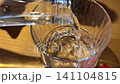 Pouring pure drinking water from glass bottle before meal at restaurant table 141104815