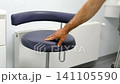 a man hand touches a chair Dental assistant stool beside treatment workstation in modern dentistry clinic clean professional interior 141105590