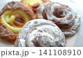 A delicious assortment of freshly baked Spanish ensaimadas topped with custard and powdered sugar. 141108910