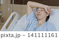 Asian female patient is holding her arm over her head in hospital room, she is anxious and stressed during treatment. 141111161