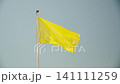 Yellow flag waves on flagpole against blue sky in sunny weather. Flag displayed by lifeguards on developed beach restricting swimming in sea and ocean. Deteriorating weather conditions for recreation. 141111259