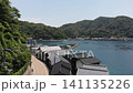 A drone takes aerial photograph of the boathouses of Ine, Kyoto, soaring directly overhead, capturing the houses lining the coast and the beautiful bay scenery. 141135226