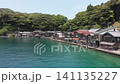 A drone slowly moves forward towards the boathouse district of Ine, Kyoto, capturing the traditional wooden buildings lining the coastline. 141135227