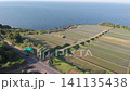 A drone-style aerial shot capturing the beautiful terraced rice fields of Arai in Ine, Kyoto, with the Sea of Japan as a backdrop, as the camera ascends directly overhead. 141135438