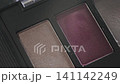 Detailed view of eyeshadow palette with vibrant colors. Editorial flatlay highlighting pigmented purple taupe eyeshadow with shimmering finish and powder details 141142249