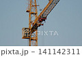 Cranes are lifting materials at a construction site in the city. The building work is ongoing under bright blue skies 141142311