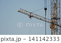 Cranes are lifting materials at a construction site in the city. The building work is ongoing under bright blue skies 141142333