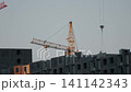 Two large cranes stand tall against the blue sky. They are positioned at a construction site 141142343