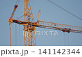 Crane operation above incomplete structure under cloudy sky. Urban development scene showing cranes and concrete core against overcast sky mood 141142344