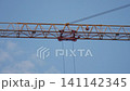 Construction crane working high above a city skyline during a clear day 141142345