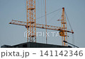 Yellow tower cranes at a construction site of a modern building 141142346