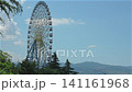 Big ferris wheel against blue sky and mountains. 141161968