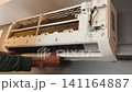 Air Conditioner Cleaning and Maintenance Service Technician Repairing Indoor AC Unit 141164887