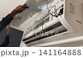 Air Conditioner Cleaning and Maintenance Service Technician Repairing Indoor AC Unit 141164888
