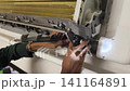 Air Conditioner Cleaning and Maintenance Service Technician Repairing Indoor AC Unit 141164891