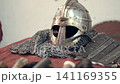 A highly detailed view of medieval ornaments. Featuring antique style, knives, a helmet, Norse symbols, accessories, irons, and a scabbard. Medieval knight's clothing and accessories. 141169355