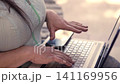 Beautiful mature Latina executive professional, with headphones and her cell phone, working on her laptop and enjoying the day, sitting in a park. Learning, home office 141169956