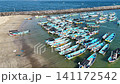 Top-down aerial footage of traditional blue wooden fishing boats neatly moored side-by-side along ropes in shallow. 141172542