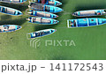 Top-down aerial footage of traditional blue wooden fishing boats neatly moored side-by-side along ropes in shallow. 141172543