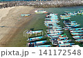 Top-down aerial footage of traditional blue wooden fishing boats neatly moored side-by-side along ropes in shallow. 141172548