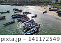 Top-down aerial footage of traditional blue wooden fishing boats neatly moored side-by-side along ropes in shallow. 141172549