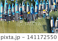 Top-down aerial footage of traditional blue wooden fishing boats neatly moored side-by-side along ropes in shallow. 141172550