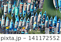 Top-down aerial footage of traditional blue wooden fishing boats neatly moored side-by-side along ropes in shallow. 141172552