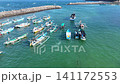 Top-down aerial footage of traditional blue wooden fishing boats neatly moored side-by-side along ropes in shallow. 141172553