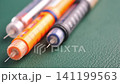 insuline pen arranged on green surface in close-up shot 141199563