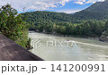 High-angle shot of a motor boat cruising along the fast-flowing Katun river surrounded by rocky banks and green pine forests in Altai Mountains, Siberia, Russia, 4k 141200991