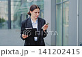 Professional Businesswoman Reviewing Information Outdoors 141202415