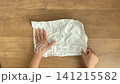 A child's hand unfolds a rolled-up piece of white paper and flattens it out - 4K silent slow-motion video 141215582