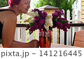 Happy woman smells fresh lilac bouquet on wooden terrace table. 141216445