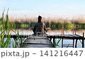 Calm woman practices yoga on wooden pier near lake. 141216447