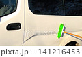 Car being washed with brush and water on sunny day in outdoor setting, 141216453