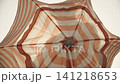 Caucasian man opens beach umbrella in front of him on camera against sky. Closeup of striped canopy of protective UV umbrella rotates and silhouette of man inside it. 141218653