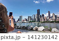 Woman with smartphone photographing manhattan skyline from roosevelt island 141230142