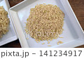 Cinematic dolly video shot showcasing steamed cooked brown jasmine rice next to raw uncooked brown rice grains presented on clean white ceramic square plates for healthy food comparison concept 141234917
