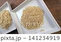 Cinematic dolly video shot showcasing steamed cooked brown jasmine rice next to raw uncooked brown rice grains presented on clean white ceramic square plates for healthy food comparison concept 141234919