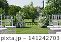 Wedding ceremony floral decorations with chairs arranged in outdoor garden 141242703