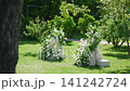 Wedding ceremony floral decorations in a lush garden setting with greenery 141242724