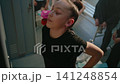 Young Female Gymnast Warms Up Beside Locker in Gymnastics Club Dressing Room 141248854