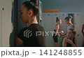Little Girl Gymnast Drinking Water from Bottle in Studio Locker Room 141248855