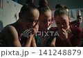 Focused Teen Gymnasts Reviewing Performance Video on Smartphone Screen 141248879