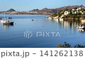 Scenic view of the calm, blue bay in Bitez, Turkey, with luxury boats anchored on the still water near a hillside resort town under a clear morning sky. High quality 4k footage 141262138