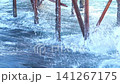 Waves continuously collide with wooden pier supports, illustrating the powerful movement of water in a coastal setting with clear blue tones 141267175