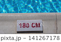 Water depth indicator reads 180 cm on the pool edge, surrounded by sparkling blue water under sunlight in a vibrant outdoor environment 141267178