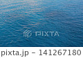 Calm ocean water displays gentle waves reflecting sunlight, creating a serene atmosphere with varying shades of blue across the surface 141267180