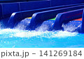 Water slides release streams of water into a bright blue pool, capturing the dynamic movement and energy of a lively water park setting 141269184